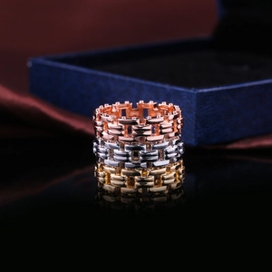 Makroaufnahme von Ringen in Roségold, Silber und Gold mit Kettenmuster auf Spiegel