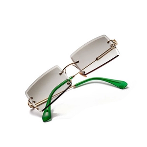 Close-up of rimless rectangular sunglasses with gold frame and green temple tips