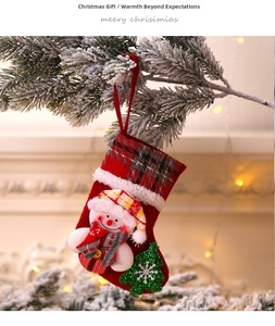 Detailed close-up of a red 3D snowman Christmas stocking hanging on snow-covered pine branches