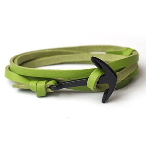 Detail of green braided leather bracelet with black anchor buckle on white background