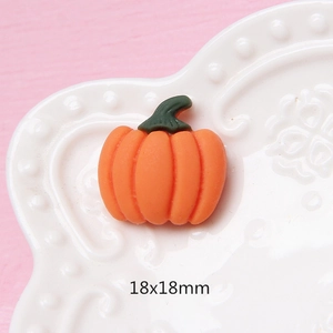 Macro di una zucca in resina opaca arancione 18x18mm su un piatto bianco con rilievi
