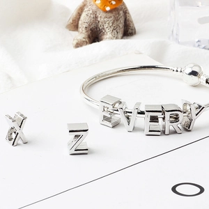 Macro view of silver alloy alphabet beads forming EVERY and individual X Z charms on a bracelet
