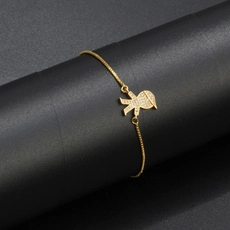 Detail of adjustable gold chain bracelet with sparkling crystal doll pendant on display
