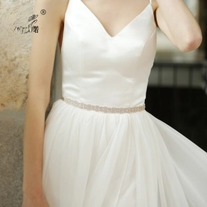 Detail of sunflower rhinestone wedding belt on white satin bridal gown with silver finish