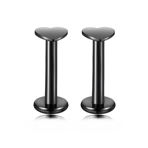 Macro detail of black heart-shaped stainless steel labret studs with polished finish