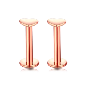 Macro shot of rose gold heart-shaped lip studs with smooth polished metal surfaces