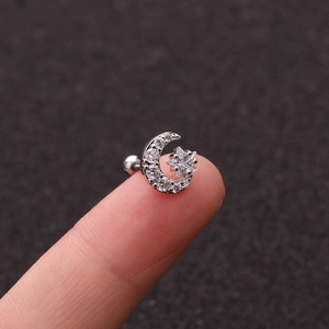 Silver crescent moon and star stud earrings with sparkling cubic zirconia on a fingertip