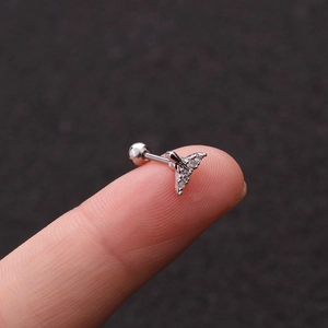 Close-up of a silver whale tail earring with cubic zirconia on a fingertip