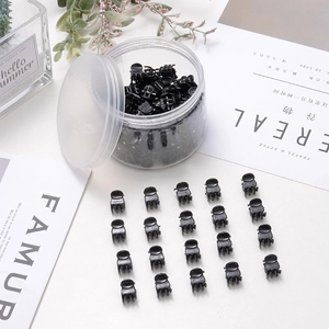 Set di mini mollette per capelli nere in un contenitore di plastica trasparente