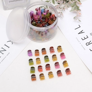 Mini fermagli per capelli a farfalla colorati disposti con un barattolo trasparente