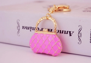 Detail of pink quilted handbag keychain with gold metal base and intricate floral handle