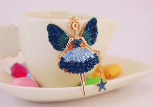 Detail eines goldenen Engel-Anhängers mit blauen Strasssteinen an einer Tasse