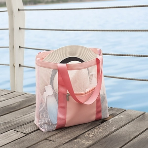 Pink mesh beach tote bag with front zipper pocket and ample storage on a wooden pier
