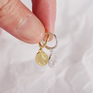 Macro detail of S925 silver religious coin earrings in gold and silver finish