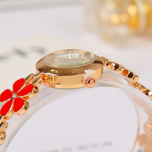 Detail of a women's gold quartz watch with red clover leaf bracelet on display