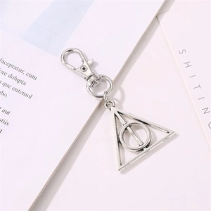 Macro shot of silver metal Deathly Hallows triangle pendant keychain on card