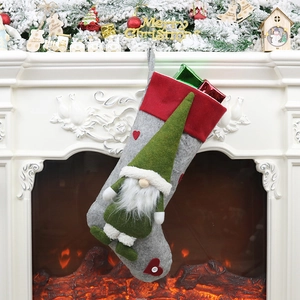 Chaussette de Noël avec gnome en feutre gris et bonnet vert sur une cheminée festive