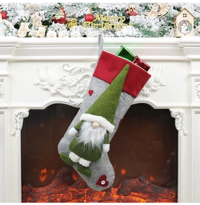 Détail d'une chaussette de Noël en feutre gris avec gnome suspendue près d'une cheminée