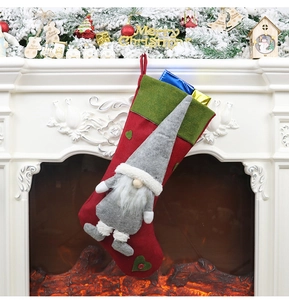 Détail d'une chaussette de Noël rouge avec poupée gnome grise sur une cheminée
