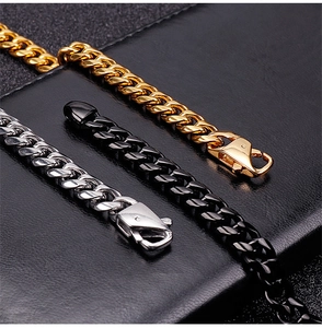Dettaglio dei bracciali a maglia cubana nei colori oro, argento e nero su pelle nera