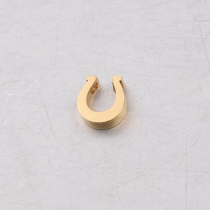 Macro detail of a horseshoe-shaped stainless steel bead with a mirror-polished golden finish