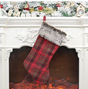Plaid Christmas stocking with faux fur trim hanging on a festive decorated fireplace