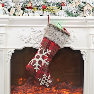 Classic red plaid Christmas stocking with white snowflakes hanging on a festive mantel