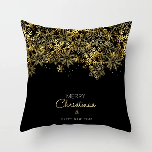 Détail d'une housse de coussin noire de Noël avec flocons dorés et texte festif