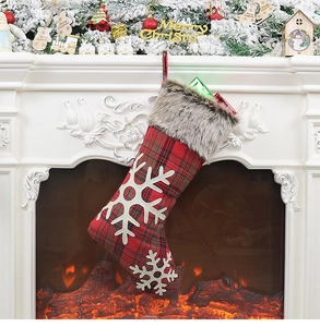 Close-up of red and black buffalo plaid Christmas stocking with snowflakes hung on mantel