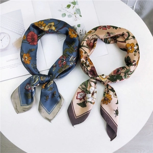 Floral silk square scarves in blue and beige with retro flower patterns on white surface