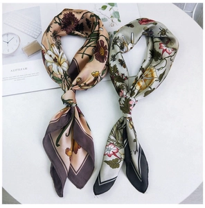 Detail of floral printed silk scarves in khaki and green with luxury aesthetic on table