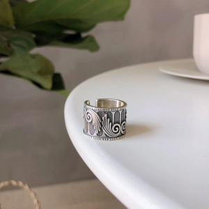Macro view of vintage silver wide ring with angel wing embossing on a white table