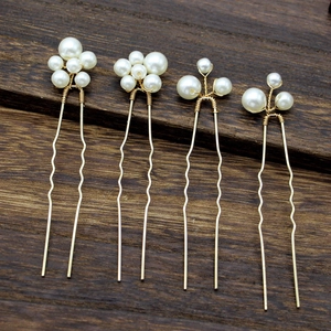 Detailed view of four vintage baroque pearl hair pins with gold wavy U-shaped metal stems