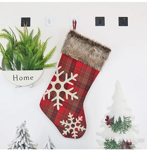 Détail d'une chaussette de Noël à carreaux rouges avec flocons de neige et fausse fourrure