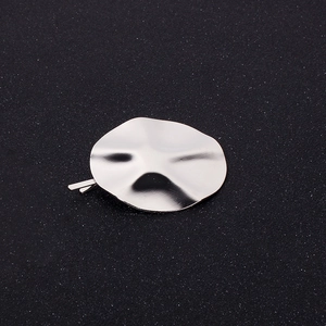 Close-up of silver metal round wavy hair clip with geometric concave-convex surface texture
