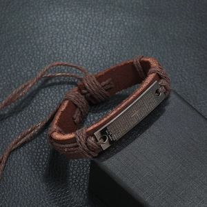Close-up of brown braided leather bracelet with Lord's Prayer engraved on metal plate