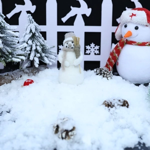 Artificial snow powder with decorative Christmas snowman scene and winter village setup