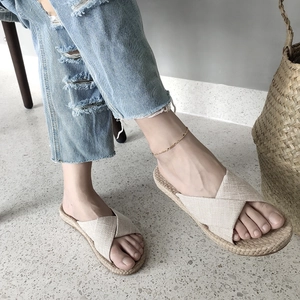 Detail of beige crossover strap fabric slides with woven texture sole for women