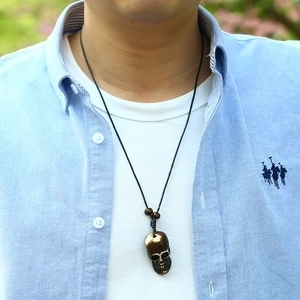 Detail of hand-woven necklace with dark brown resin skull pendant and black cord