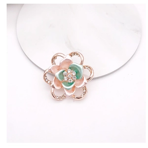 Macro shot of rose gold flower brooch with pink and mint enamel and sparkling rhinestones