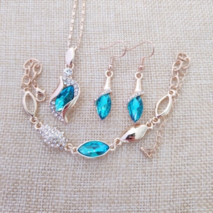 Detailed shot of gold jewelry set featuring blue teardrop stones and white crystals