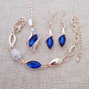 Detail view of water-drop blue crystal jewelry set with gold plating on beige burlap