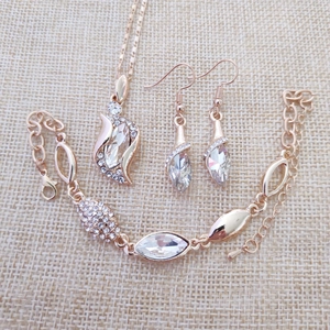 Overhead view of rose gold angel crystal jewelry set including necklace, bracelet and earrings