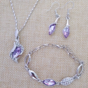 Macro shot of silver jewelry set with purple crystals and sparkling diamonds on linen