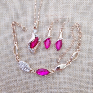 Flat lay of elegant gold-plated leaf jewelry set with rose red gems and clear crystals