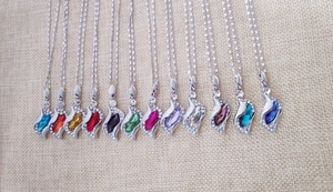 Detailed collection of crystal necklaces in twelve colors hanging on linen background