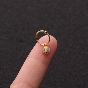 Vista macro di un piccolo orecchino a cerchio d'oro con pendente a sfera in zircone