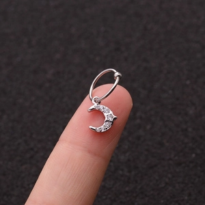 Dettaglio di un orecchino a luna in argento con zirconi scintillanti su un dito