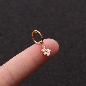 Primo piano di un piccolo cerchio dorato con pendente a foglia in zircone sulla punta del dito