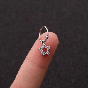 Orecchino a cerchio in acciaio argento con ciondolo a stella in zircone sul dito
